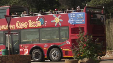 Pan-left-with-red-double-decker-tour-bus-driving-past-in-Cape-town,-RSA