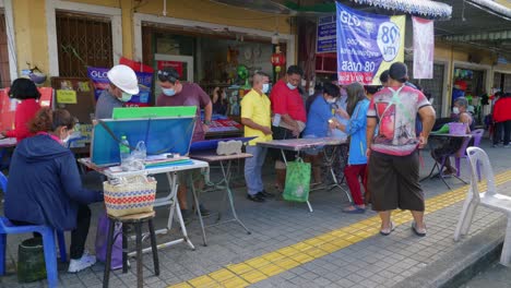 Foto-De-Personas-Que-Compran-Lotería-En-Un-Puesto-Al-Borde-De-La-Carretera-En-La-Provincia-De-Songkhla,-Tailandia-Durante-El-Día