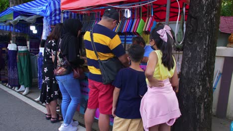 Static-shot-of-locals-busy-buying-clothes-and-gift-items-from-roadside-stall-in-Khlong-Hae-floating-market-in-Songkhla-province,-Thailand