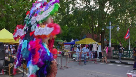 Low-angle-shot-of-a-female-performer-dancing-at-the-entrance-of-Khlong-Hae-floating-market-in-Songkhla-province,-Thailand-at-daytime