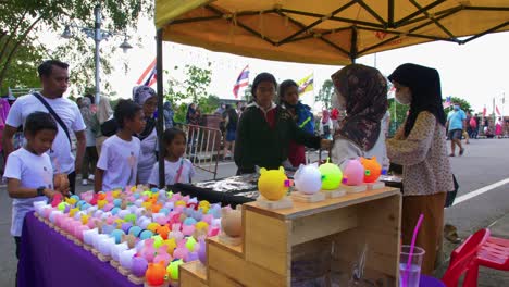 Static-shot-of-roadside-stall-selling-cute-colorful-toy-souvenirs-in-crowded-Khlong-Hae-floating-market-in-Songkhla-province,-Thailand