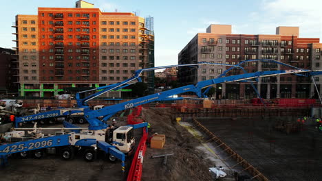 Aerial-view-in-front-of-concrete-pumps-at-a-construction-site---low,-tracking,-drone-shot