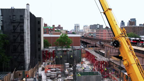 Vista-Aérea-Pasando-Una-Grúa-Levantando-Materiales-En-Un-Sitio-De-Construcción-En-Nueva-York