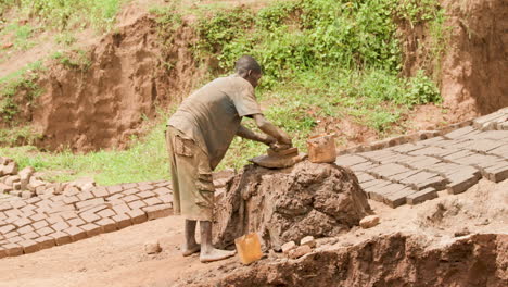 Medium-long-shot-of-brick-worker-forming-clay-in-brick-shape-and-laying-on-the-ground