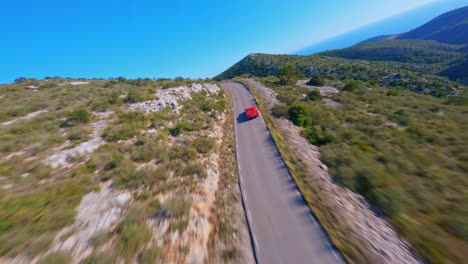 Pintoresca-Vista-Aérea-Siguiendo-Un-Ferrari-Rojo-Mientras-Viaja-A-Lo-Largo-De-Una-Pintoresca-Carretera-De-Montaña