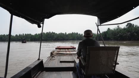 Delta-Del-Mekong,-Vietnam,-10-De-Diciembre-De-2022---Paseo-En-Barco-Por-El-Río-Mekong,-Saigon:-Hombre-Conduciendo-Río-Arriba-A-Través-De-Cocoteros