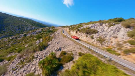 Vista-Aérea-De-Un-Ferrari-Rojo-Conduciendo-Por-Una-Pintoresca-Carretera-De-Montaña-En-España