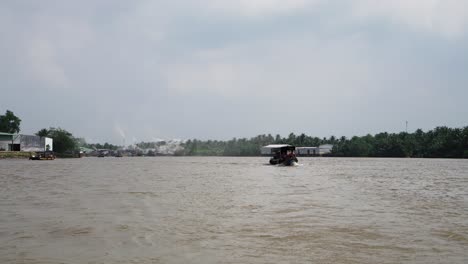 Mekong-Delta,-Vietnam,-December-10-2022---driving-boat-upstream-on-the-Mekong-River,-passing-through-coconut-palms-in-4K