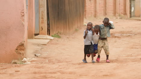 Tiro-Largo-En-Cámara-Lenta-De-Tres-Niños-Caminando-Por-La-Calle-De-Tierra-Con-Los-Brazos-Envueltos-Alrededor-Del-Otro