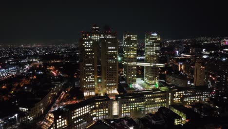 Vista-Aérea-Lejos-Del-Complejo-Arcos-Bosques,-De-Noche-En-La-Ciudad-De-México---Retroceso,-Disparo-De-Drones