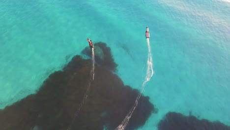 Las-Imágenes-De-Un-Dron-Siguen-A-Dos-Personas-Que-Navegan-En-Las-Aguas-Cristalinas-Y-Azules-De-Un-Océano-En-Una-Tabla-Flotante.