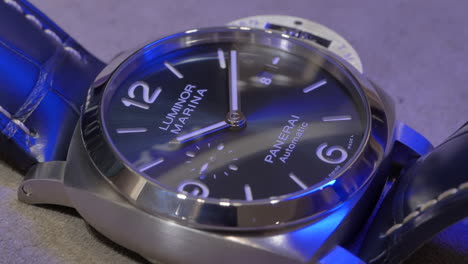 Elegante-Reloj-De-Pulsera-Marítimo-Plateado-Panerai-Con-Iluminación-Azul-Que-Brilla-En-La-Esfera,-Primer-Plano