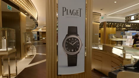 Dentro-De-Una-Elegante-Tienda-De-Relojes-Con-Una-Columna-De-Exhibición-De-Ventas-Minoristas-De-Piaget-Detrás-Del-Mostrador-De-Atención-Al-Cliente