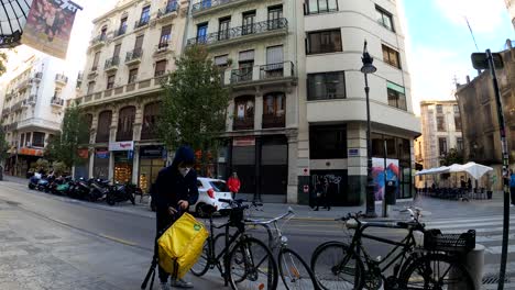 Glovo-bike-courier-with-face-mask-arriving-at-Starbucks-restaurant-to-pick-up-food-order-to-deliver---Valencia,-Spain