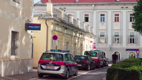 A-man-on-an-electric-roller-passing-the-police-station-in-Kiki-Kogelnik-Gasse-in-the-historic-city-center-in-Klagenfurt,-Carinthia,-Austria