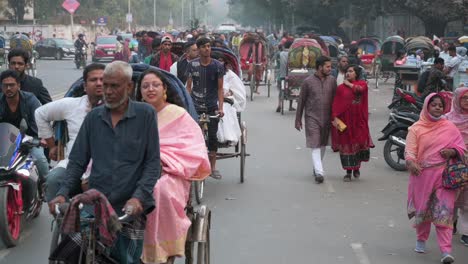 Slow-motion-footage-of-Bangladeshi-commuters-riding-on-rickshaws-while-pedestrians-share-the-road