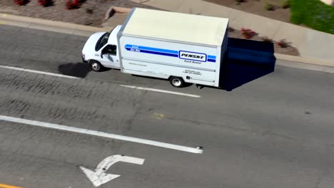 Bird-eye-drone-shot-following-Penske-rental-van-driving-on-highway