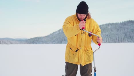 Un-Tipo-Con-Un-Taladro-De-Pesca-En-Hielo-Cavando-Un-Agujero-En-Un-Lago-Congelado