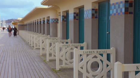 Cabañas-De-Playa-Junto-Al-Mar-De-Normandía-Y-Paseo-Marítimo-De-Madera-Les-Planches-Con-Famosos-Nombres-De-Actores-Y-Directores-En-Deauville,-Francia