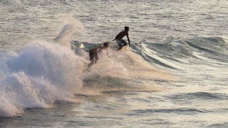 Dos-Surfistas-Comparten-Olas-En-El-Oleaje-De-La-Costa-Sur-Deslizándose-Sobre-Aguas-Doradas