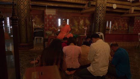 Buddhist-monk-blessing-people-by-splashing-water-on-their-heads-in-Songkran-ceremony,-Thailand