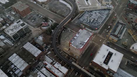 Aerial-overview-of-a-train-moving-over-Halstead-street-and-North-avenue-on-elevated-rails-in-gloomy-Lincoln-Park,-Chicago,-USA