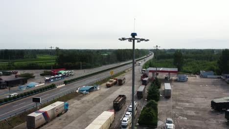 Drohnen-Luftaufnahmen-über-Einer-Autobahn-Mit-Vorbeifahrendem-Verkehr-Und-Gleisparkplatz,-Aufgenommen-In-Der-Provinz-Hebei,-China