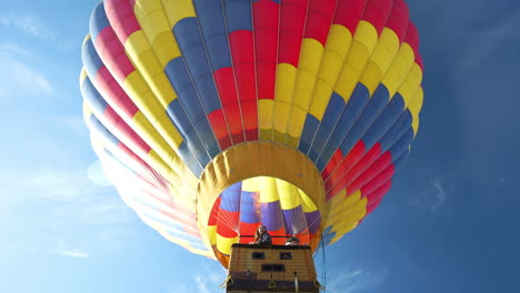 Globo-De-Aire-Caliente-Con-Gente-En-La-Cesta-Elevándose-Bajo-El-Cielo,-Vista-De-ángulo-Bajo