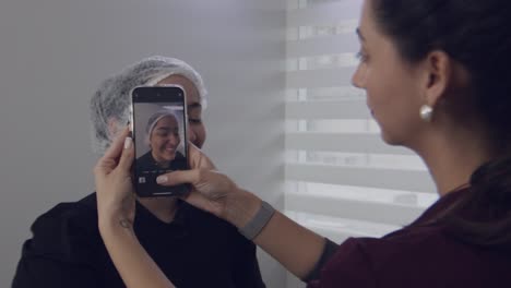 Nurse-taking-picture-of-a-woman-patient-wearing-bouffant-cap-in-doctor's-clinic,-slow-motion