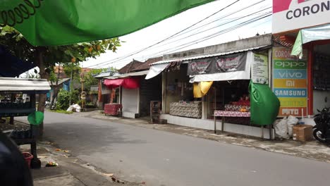 Scooters,-Motorbikes-and-People-Driving-Bali-Road-in-Batubulan-Sukawati-Gianyar-during-Daytime,-a-local-street-in-a-traditional-Balinese-Village,-Indonesia,-Southeast-Asia