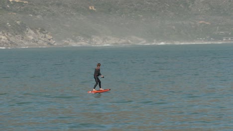 Der-Lehrer-Unterrichtet-Power-Tragflächenboot-Surfbrett-Vor-Der-Bergigen-Küste