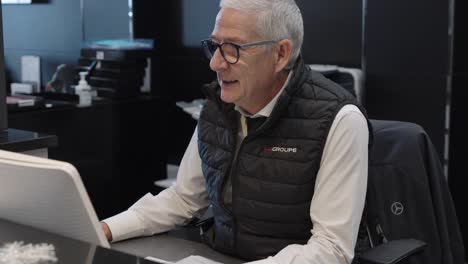 A-old-men-with-glasses-from-the-Mercedes-dealership-works-at-her-desk