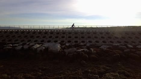 Toma-En-Cámara-Lenta-De-Un-Hombre-Montando-Su-Bicicleta-Junto-Al-Mar