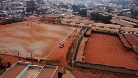 Vista-Aérea-Acercándose-A-La-Gente-Jugando-Fútbol-Callejero-En-La-Ciudad-De-Yaundé,-Camerún