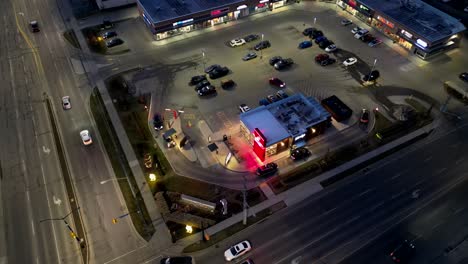 Toma-En-órbita-Aérea-De-Wendy&#39;s-Drive-Thru-En-La-Noche-Iluminada-Por-Luces-De-La-Calle-Y-Automóviles