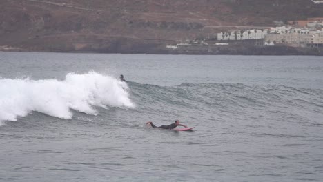 Gran-Canaria-Spain---February-9-2023:-Surfers-try-to-ride-waves-at-Las-Canteras-beach-in-Las-Palmas-de-Gran-Canaria,-Spain