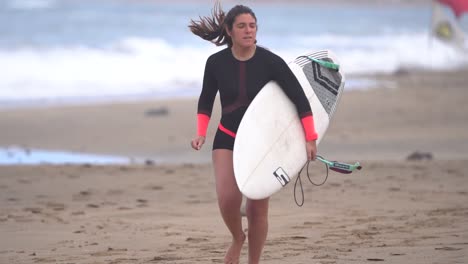 Gran-Canaria-Spain---February-9-2023:-Surfer-woman-run-at-the-beach-to-catch-waves-at-Las-Canteras-beach-in-Las-Palmas-de-Gran-Canaria,-Spain