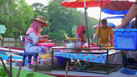 Vista-Estática-De-Dos-Mujeres-Con-Máscaras-Que-Venden-Comida-Callejera-Oriental-Tradicional-Local-En-Un-Pequeño-Puesto