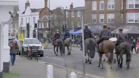 People-riding-on-horses-on-public-street-in-Wimbledon-central-London-on-a-cloudy-day