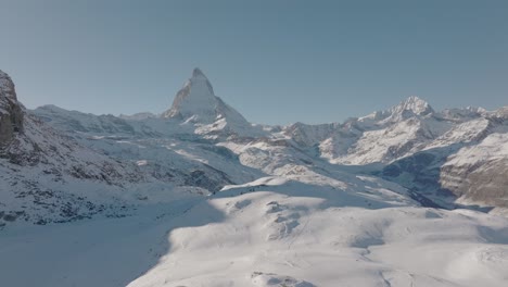 Mujer-Joven-Feliz-En-Roca-Nevada-Levantando-Los-Brazos-Eufóricamente-En-El-Impresionante-Panorama-De-Montaña-De-Los-Alpes-Suizos