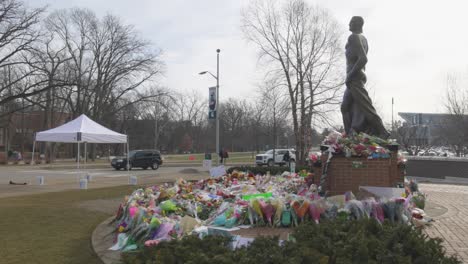 Spartanische-Statue-Auf-Dem-Campus-Der-Michigan-State-University-Mit-Blumen-Nach-Der-Massenerschießung-Im-Jahr-2023,-Mit-Gimbal-Video-Dahinter