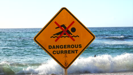 Un-Hombre-Nada-Frente-A-Un-Cartel-De-Corriente-Peligrosa-En-Bondi-Beach,-Sydney,-Australia