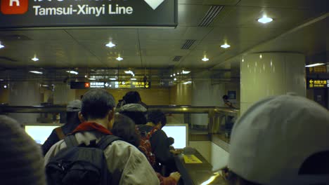 Taipei,-Taiwan---Jan-28th-2019:-crowds-of-people-passengers-taking-metro-rail-road-train-ride-walking-slow-one-by-one-in-order-underground-tunnel-with-escalator-toward-Tamsui-Xinyi-red-Line-bmpcc