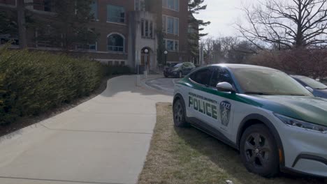 Edificio-Sindical-En-El-Campus-De-La-Universidad-Estatal-De-Michigan,-Lugar-De-Un-Tiroteo-Masivo-En-Febrero-De-2023-Con-Un-Auto-De-Policía-De-Msu-Y-Un-Video-Cardán-Caminando-Hacia-Adelante