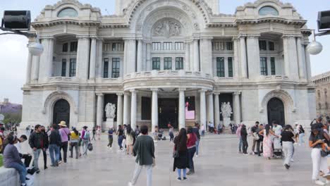 Ein-Breiter-Zeitlupen-Dolly-In-Aufnahme-Von-Menschen,-Die-An-Einem-Klaren-Tag-Mit-Blauem-Himmel-Vor-Dem-Palacio-De-Bellas-Artes-In-Mexiko-Stadt-Spazieren