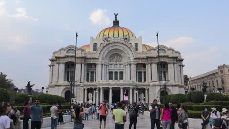 Una-Amplia-Rodada-En-Cámara-Lenta-Del-Palacio-De-Bellas-Artes-En-La-Ciudad-De-México-Con-Algunas-Personas-Caminando,-En-Una-Tarde-Clara-Con-Un-Cielo-Azul