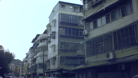 Taipei,-Taiwan---Jan-28th-2019:-look-up-walking-view-of-ghetto-old-dirty-asian-apartment-building-with-old-simple-electricity-poles-and-cables-hanging-across-in-sky-and-all-bared-window-balcony