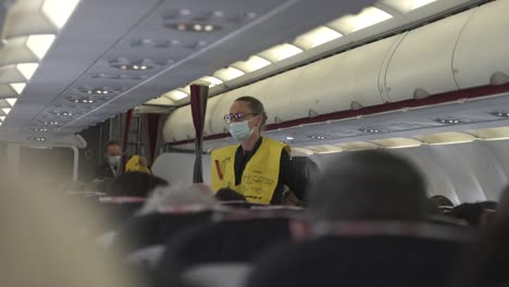 Stewardess-at-Air-France-777-jet-explaining-safety-floating-vests-to-passengers-in-cabin,-Locked-shot
