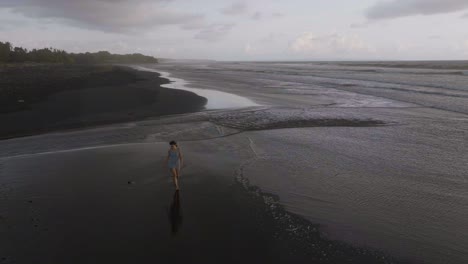 Frau,-Die-Am-Atemberaubenden-Exotischen-Schwarzen-Sandstrand-In-Lovina,-Bali,-Spaziert