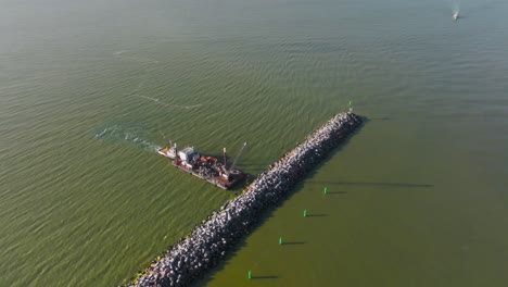 Vista-Aérea-Se-Forma-Y-Fija-Un-Rompeolas-Con-La-Ayuda-De-Un-Equipo-Especial-Y-Un-Barco